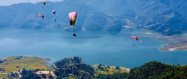  Paragliders soaring high above the beautiful landscape of Pokhara.