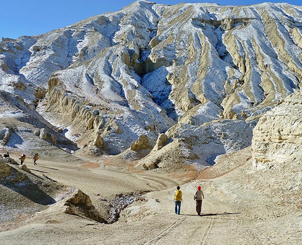 Elevate Trek-Two trekkers exploring Upper Mustang, with two porters leading the way.