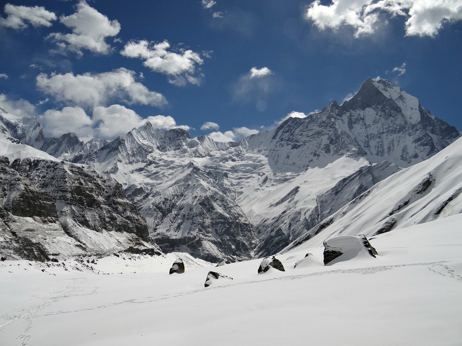 Elevate Trek- A snowy mountain range with blue sky and clouds