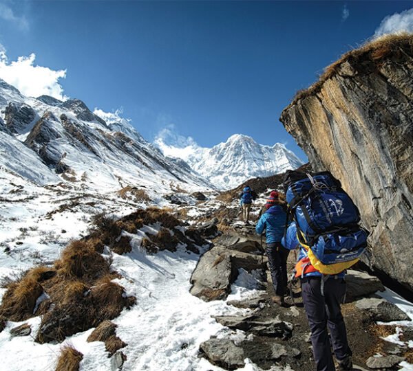 Elevate Trek- Two Trekkers and one porters walking on trail of Annapurna Base Camp