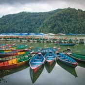 Elevate Trek- Group of boats on Phewa Lake, Pokhara, with a single boater in the center of one boat