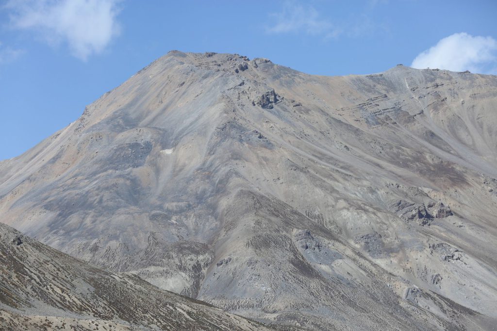 High mountain peak with rocky terrains under a clear blue sky, perfect for adventure enthusiasts.