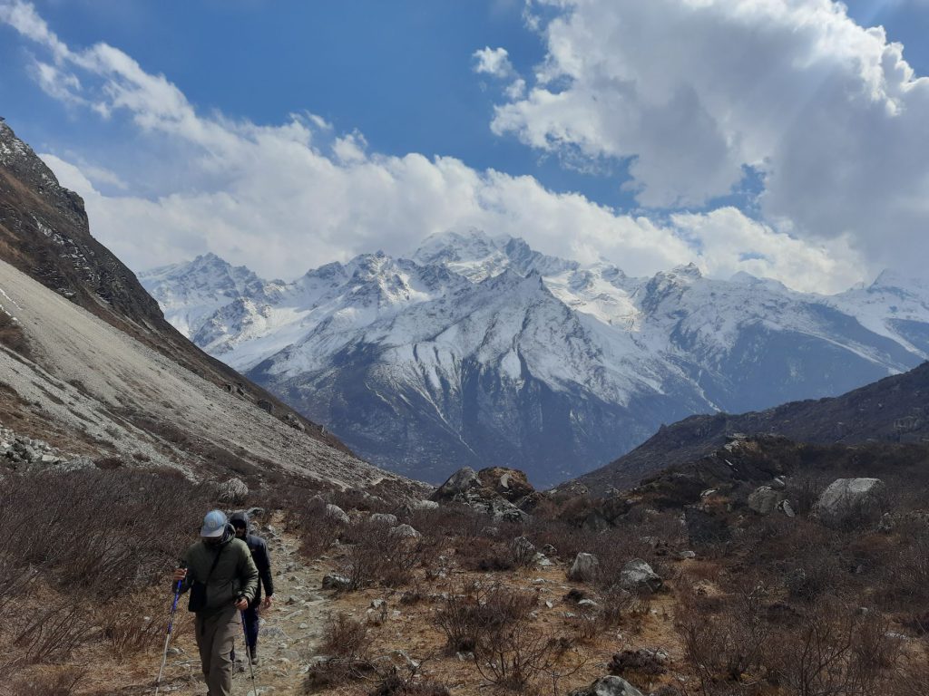 Scenic hike in Nepal's Langtang Valley with snow-capped mountains and cloudy skies.