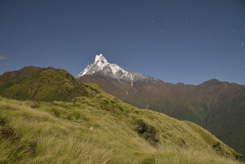 Breathtaking view of snow-capped mountains under a starry night sky, showcasing serene nature.