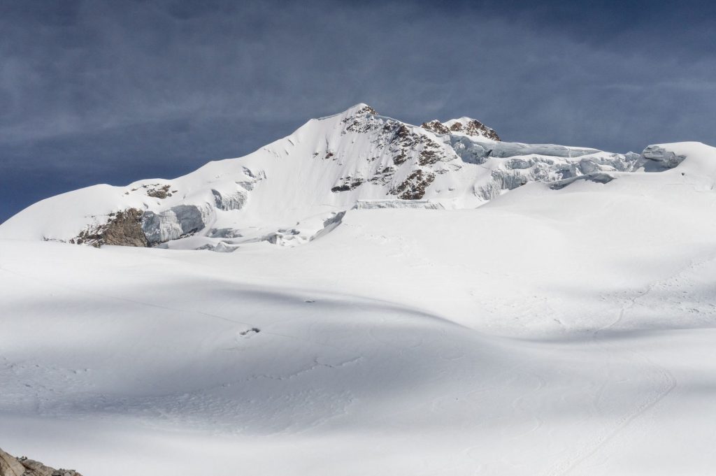 Majestic snow-covered mountain range under a clear blue sky, captured in winter.