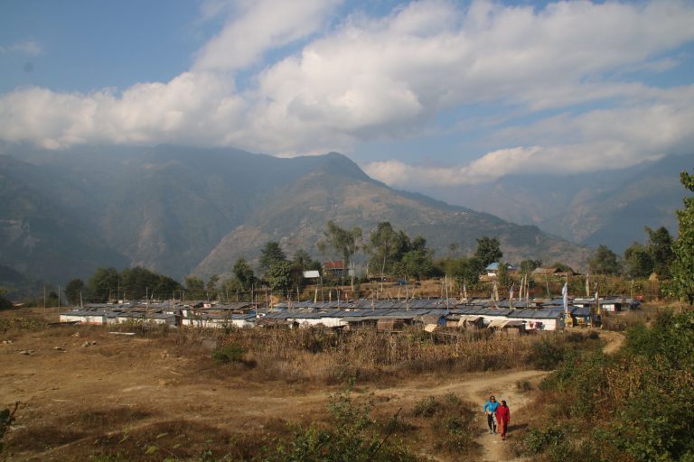 View of rural mountain village with clear skies and agricultural fields.