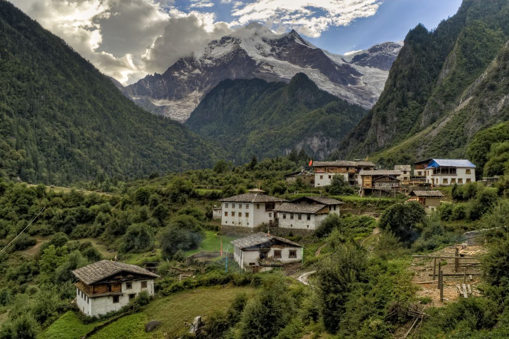 Picturesque village nestled in the Himalayas with lush greenery and towering mountains.