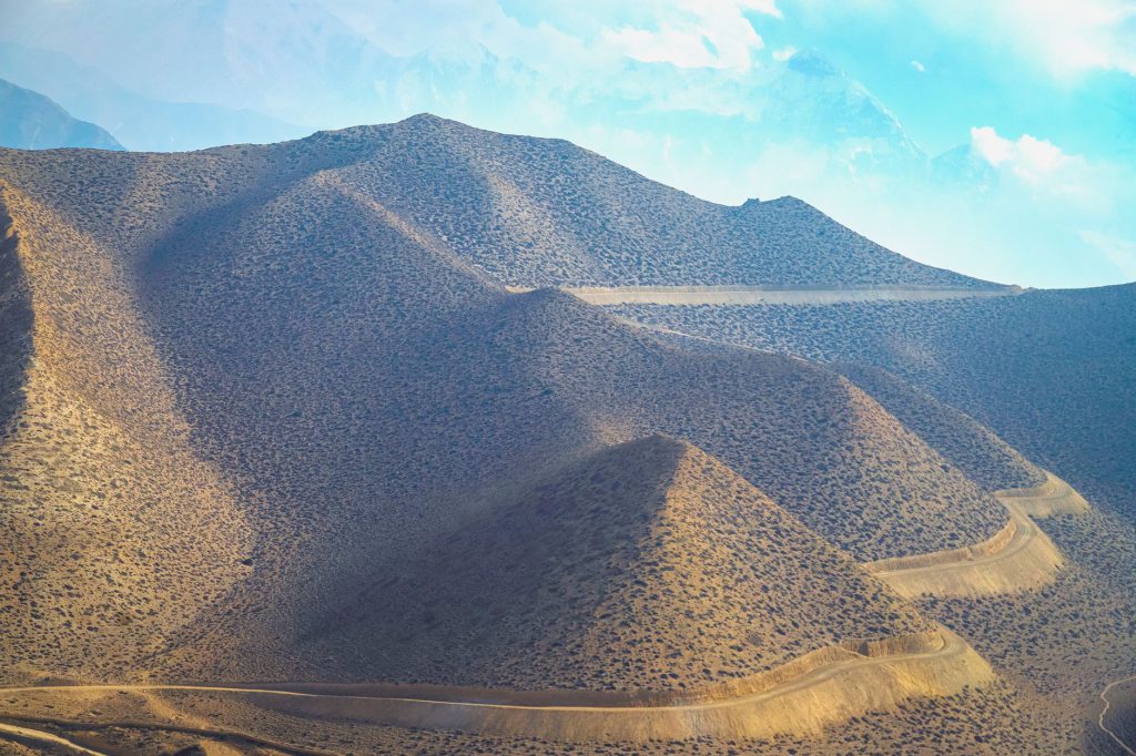 Beautiful view of rolling hills and winding paths in Upper Mustang, Nepal, showcasing a remote and rugged terrain.