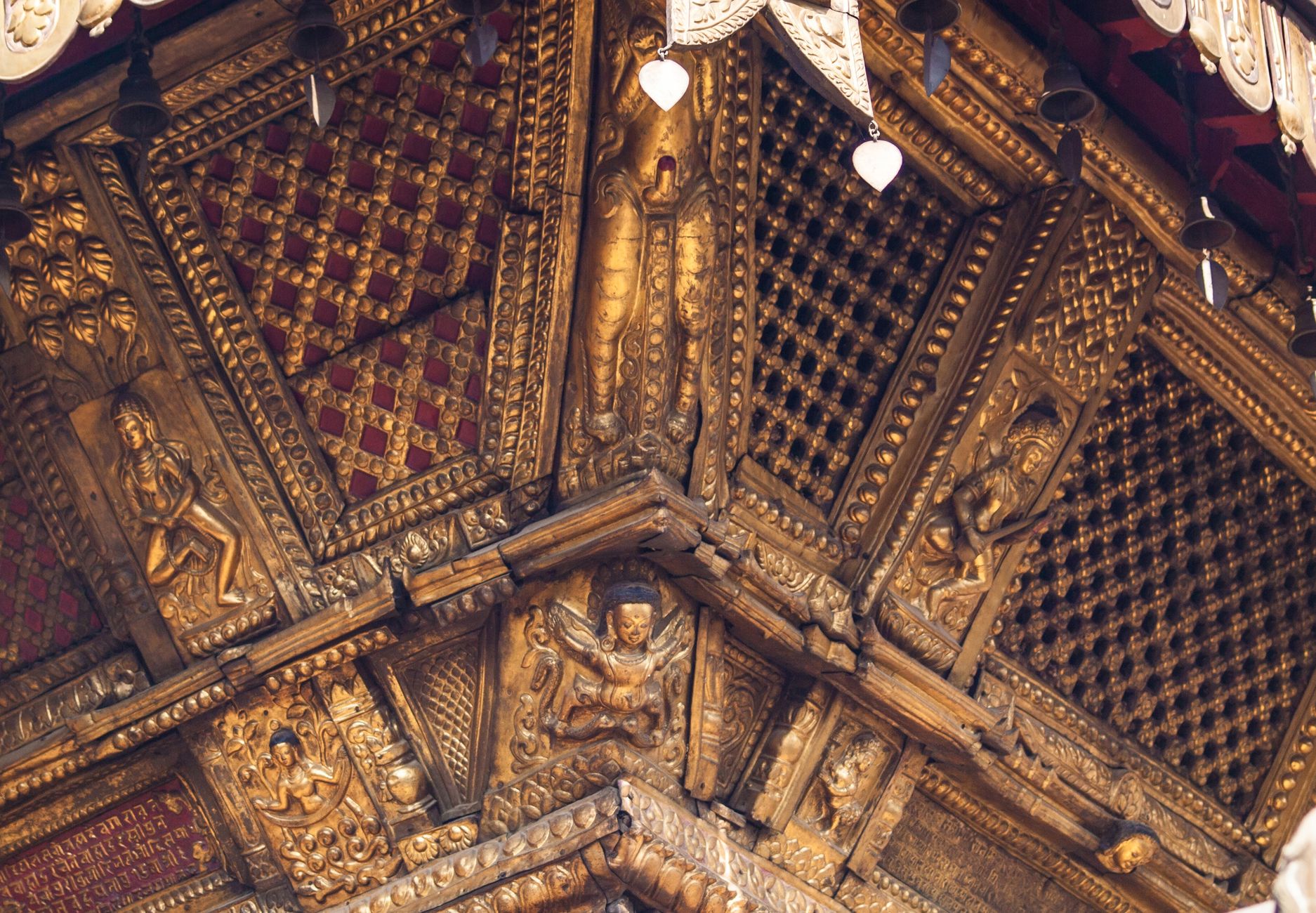 Close-up view of an ornate golden wooden temple roof with intricate carvings.