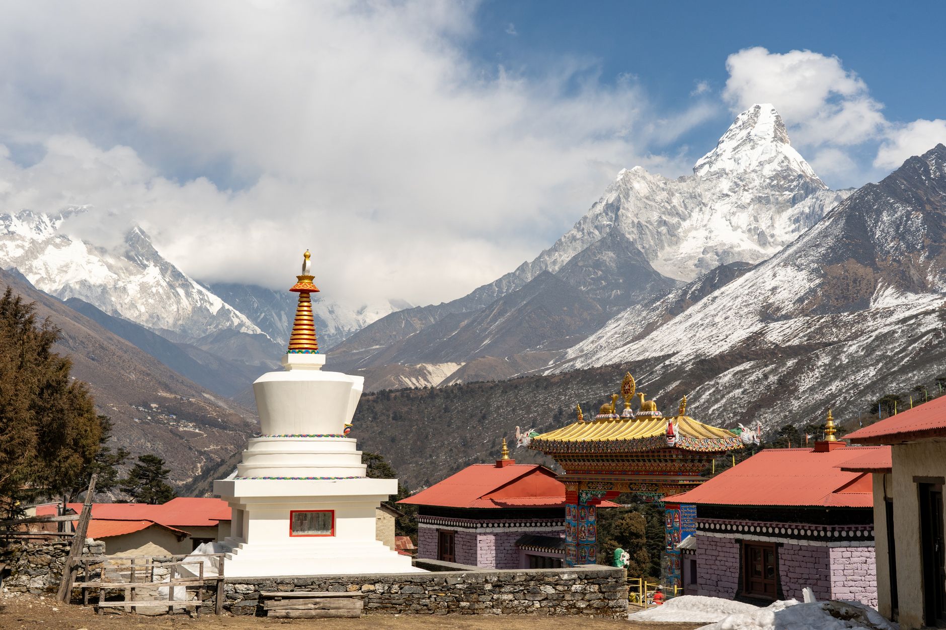 Stupa and traditional buildings with Himalayan mountains in background, showcasing serene beauty.