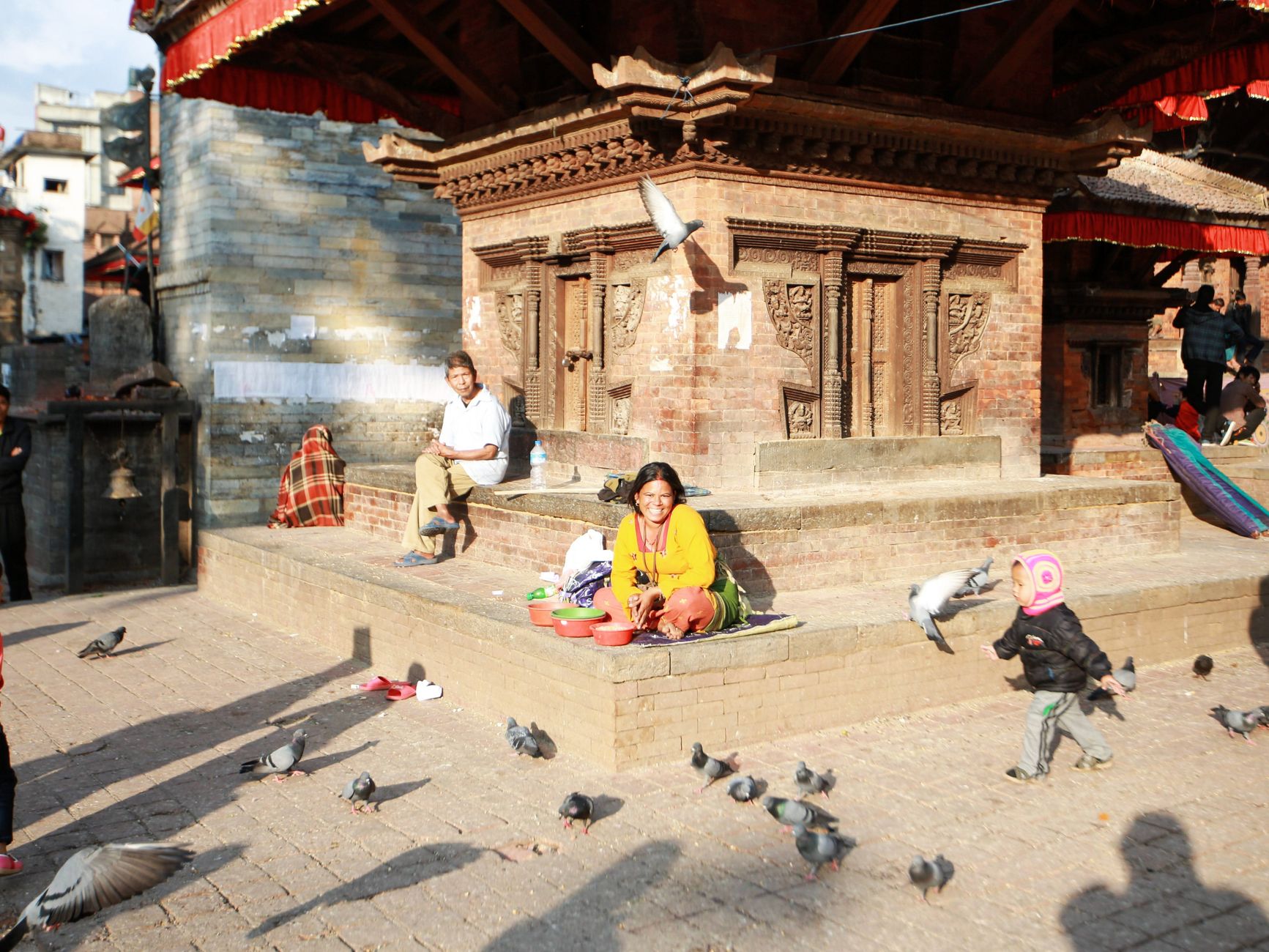 Vibrant scene of people and pigeons at a historic Buddhist shrine in a bustling city.